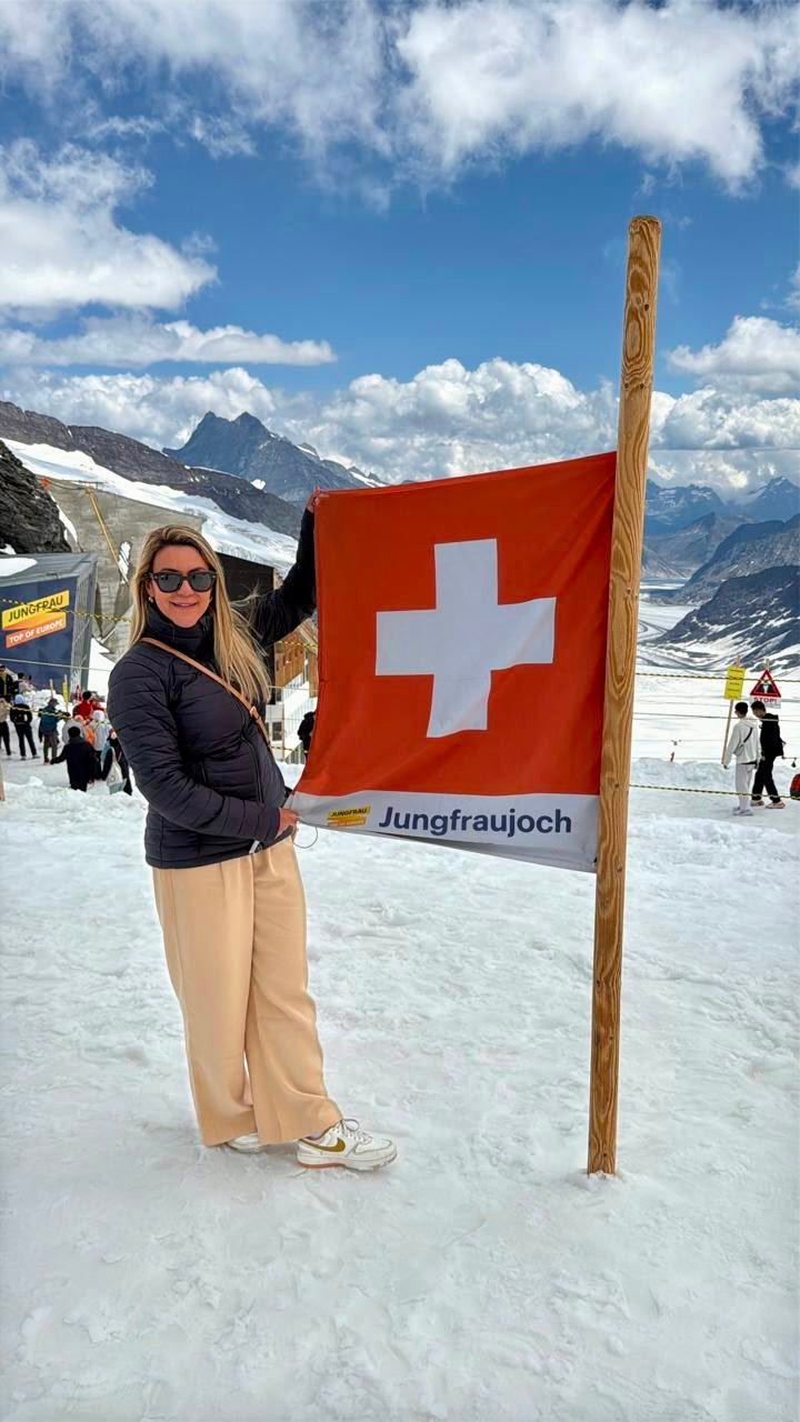 Carolina Andrade ao lado da bandeira suíça no Jungfraujoch, nos Alpes